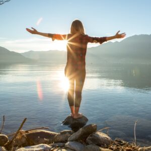 Woman standing next to lake at sunset