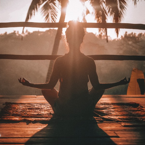 Woman meditating next to lake at sunset